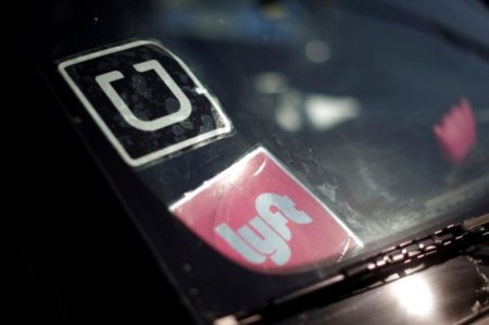 A driver displays Uber and Lyft ride sharing signs in his car windscreen in Santa Monica, California, U.S.